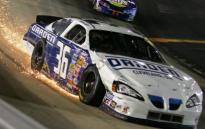 A NASCAR grinds sparks after a collision with a track wall